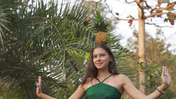 Young woman keeps a balance with a pineapple on her head. High quality photo