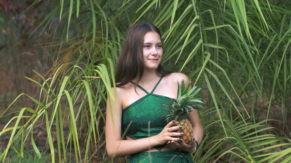 young woman posing with a pineapple in the jungle. High quality photo