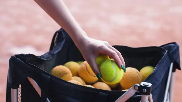young womans hand retrieving tennis balls from a bag. High quality photo