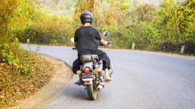 Asya 'da eski bir motosiklet süren genç bir adam. Yüksek kalite fotoğraf