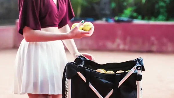young woman retrieving spare tennis balls in white skirt. High quality photo
