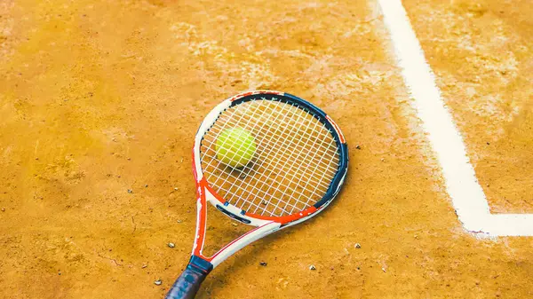 tennis racket lying on a tennis ball on the ground. High quality photo