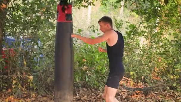 스포츠맨은 정글의 배경에 가방을 타격하고있다 고품질 비디오 — 비디오