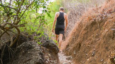 Siyahlar giymiş genç bir adam tropik bir yolda yürüyor. Yüksek kalite fotoğraf