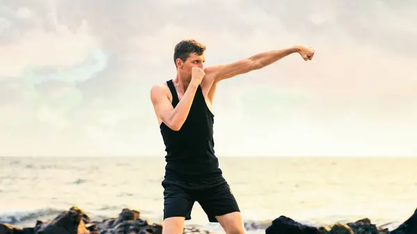 young man in a black sportswear boxing on the coastline. High quality photo