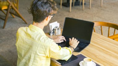 Bir kafede dizüstü bilgisayarda yazan genç bir adam. Yüksek kalite fotoğraf