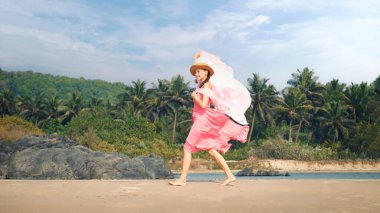 Genç bir kadın tropik ormanların arka planında bir perdeyle yürüyor. Yüksek kalite fotoğraf