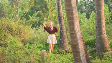 Genç bir kadın, tropik ormanlarda tenis topuyla ayakta duruyor. Yüksek kalite fotoğraf