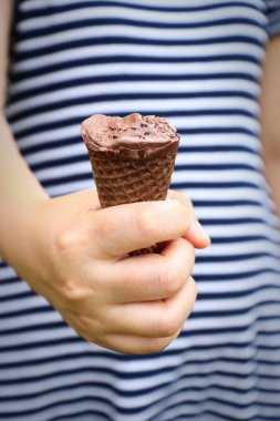 it is lady hand holding melted chocolate ice cream and missing bite.