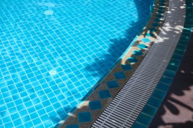 swimming pool edge under sunlight and shade.