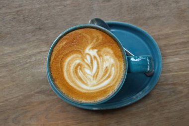 one cup of latte with spoon on wooden table.