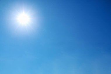 Parlak güneş açık mavi gökyüzünde parlıyor.