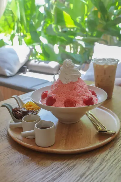Meyveli, kırmızı çilekli buz ya da buzlu kahveyle servis edilen sos ve reçelli beyaz kâse üzerine bingsu..