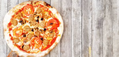Top view of Pepperoni pizza on grunge gray wooden background or table with right copy space. Cooking ingredient with tomato, mushroom and Thai sausage. This food baked by use charcoal stove.  