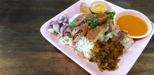 用米饭 煮熟的鸡蛋片 蔬菜和酸酱汁 用粉红的盘子 深褐色的木制背景或有复制空间的桌子把炖肉腿包好 泰国当地和街头食物 — 图库照片