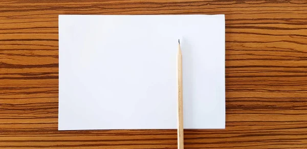 白い紙と茶色の鉛筆は テキストを埋めるためのコピースペースと木製のテーブルに置きます オブジェクトの概念 — ストック写真