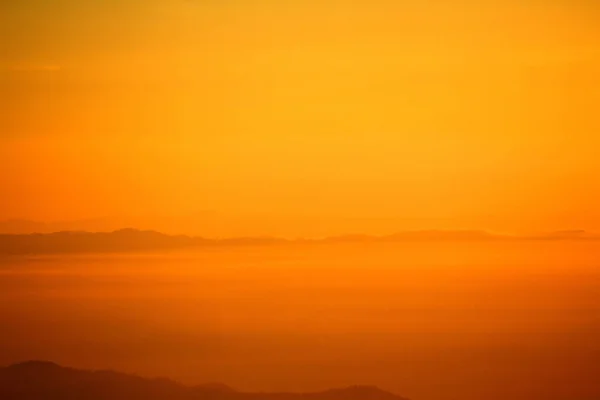 Beautiful orange sunshine or sunrise in morning with silhouette of mountain for background at Doi Chiang Dao, Doi Luang Chiang Dao, Chiangmai, Thailand. Landmark for travel and Beauty of Nature