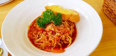 Kıyma, tavuk ya da biftekle spagetti, ahşap masada beyaz tabakta tatlı domates soslu kızarmış tereyağlı ekmek. İtalyan yemeği ve öğle yemeği vakti lezzetli yemekler.. 