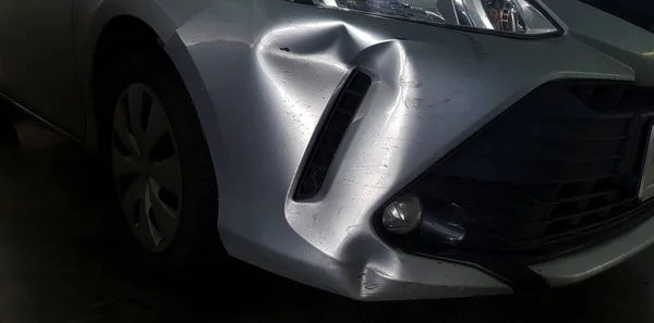 事故后灰色 灰色或青铜汽车上的划痕或凹痕 前保险杠受了伤 停车场和修理概念 图库图片