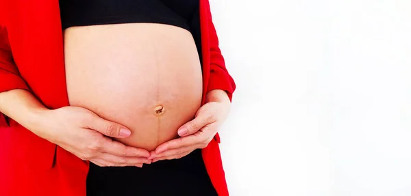 Close Up pregnant woman wearing red suit holds hands on swollen belly isolated on white background and copy space with clipping path. Pregnancy 7-9 months, motherhood, love, expectation and car