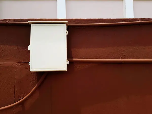 White electrical distribution box installed on the brown concrete wall. Industrial and Object concept