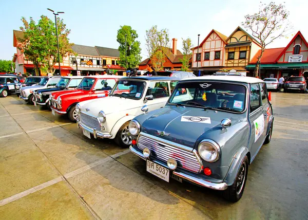 Ayutthaya, Tayland - 6 Aralık 2023: Birçok renkli klasik Mini Cooper park yeri ve arka planda ev ve gökyüzü olan eski araba festivalinde gösteriliyor. Ulaşım ve Vintage Araç konsepti