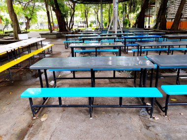 Kantin ve açık hava restoranlarında sarı ve mavi banklı bir grup boş masa.. 