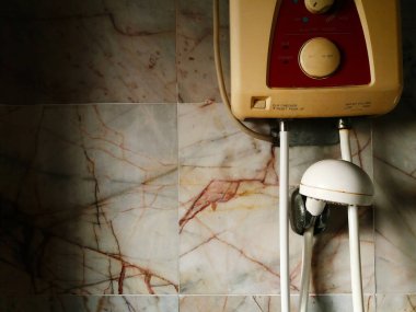 Tuvaletin içindeki beyaz, gri ya da gri mermer duvara su ısıtıcısı yerleştirilmiş. Suyu ısıtmak ve kışın duş almak için tuvalet ya da tuvalet. Kopyalama alanı olan elektronik aygıt. 