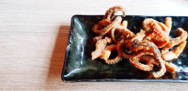 Kızarmış somon derisi fileto siyah tabak içinde ahşap masa üzerinde fotokopi alanı ile birlikte. Lezzetli, Balık, hala yemek ve aperatif konsepti..  