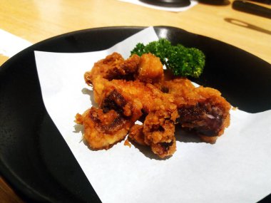 Japon restoranında kızarmış kalamar dokunaçları siyah tabak ya da tabakta. Fotokopi alanı olan deniz ürünleri..