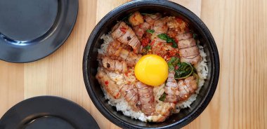 Kızarmış Tayland fesleğenini kerevit ve yumurta sarısını ahşap masadaki sıcak siyah yumurtanın içinde müşteriye servis etmek ve yemek için. Baharatlı ve Asyalı yemek stilinin düzlüğü.. 