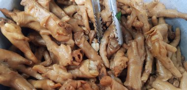 Paslanmaz çelik kasede paslanmaz maşayla kaynatılmış ya da buğulanmış tavuk ayağı ya da bacağı satılık ve yerel gıda pazarında müşteriye servis ediliyor. Lezzetli ya da lezzetli yemekler ve hayvan konseptinin bir parçası.. 