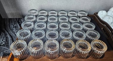 Müşteriler ve misafirler için içme suyu hazırlamak için siyah ahşap tepsiye baş aşağı yerleştirilmiş birçok bardak su. Tabak ve nesne desen sanatı.