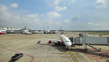 Bangkok, Tayland - 22 Mayıs 2025: Park etmiş ve yolcu bekleyen uçak mavi gökyüzü ve Donmueng havaalanında fotokopi alanı olan bina arka planına sahip.. 