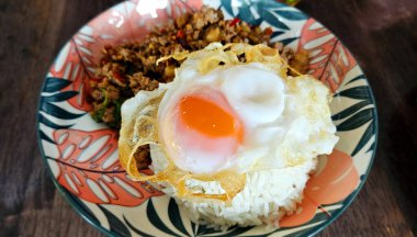 Tayland usulü sahanda yumurtayı kutsal fesleğenle karıştırın ve ahşap masada kurutulmuş acı biber ezmesi. Tayland 'da ünlü yemekler..