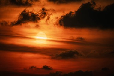 Güneş 'in bulutlarda saklandığı kırmızı turuncu gün batımı. Parlayan ışık çizgisi Güneş diskini yatay olarak geçiyor. Fotoğrafı kapat. Tayland