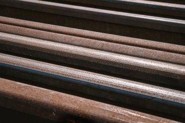 Birçok kişi eski rayların değiştirilmesi için farklı uzunluktaki paslı rayları bir zeminde depoladı. Çapraz yerleştirme Fotoğrafı kapat