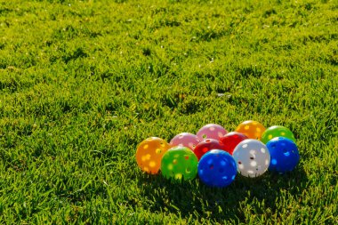 Birçok açık renkli plastik golf topları ile yeşil çimlerde bir araya toplanmış delikler. Evde golf antrenmanı yapıyorum. Fotoğrafı kapat.