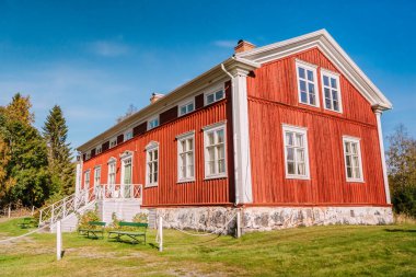 Geleneksel kırmızı İskandinav ahşap evi, yemyeşil bir ortamda. RATAN İSVEÇ - 21 EYLÜL 2024
