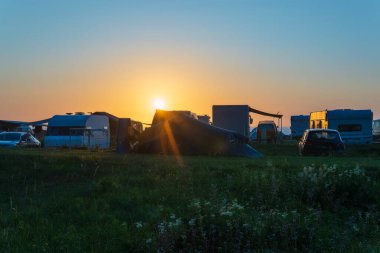 Kampçılar ve kervanlar, çimenli bir arazide batan güneşe karşı siluet oluşturdular. Sıcak ışık, huzurlu ve huzurlu bir atmosfer yarattı..