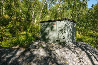 Norveç 'te yemyeşil orman bitkileriyle çevrili ücra bir bölgede elektrik kaynağı sağlayan elektrik trafosu istasyonu elektrik dağıtımı için gerekli altyapıyı sergiliyor.