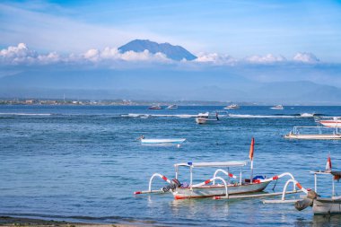 Sanur plajı Bali Endonezya 'dan Agung volkan manzarasının tepesinde, volkanın sadece bir kısmı görülebilir, önplanda birçok uzun kuyruklu tekne var..