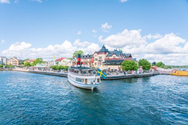 Güneşli bir yaz gününde İsveç 'teki Vaxholm Limanı' ndan kalkan yolcu feribotu. VAXHOLM, İSVEDEN - 10 Temmuz 2022