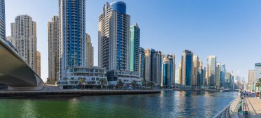 Dubai Marina 'nın panoramik manzarasında modern gökdelenler suya yansıyor. Canlı şehir manzarası mimari harikaları ve hareketli şehir yaşamını vurguluyor. Dubai BAE 27 Mart 202