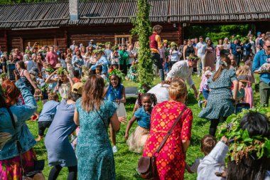 Turistler ve yerliler Gammlia, Umea, İsveç 'te yaz dönümünü güneşli bir günde çocuklarla dans ederek ve meyhane etrafında oynayarak kutluyorlar. UMEA, GAMLIA, İSVEÇ 23 HAZİRAN 2023
