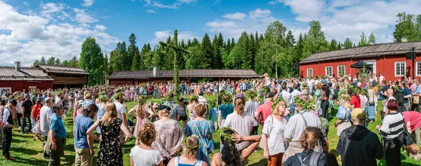 Gammlia, Umea 'da yaz ortasında coşkulu bir kalabalık yemyeşil ve tarihi kırmızı binalar arasında güneşli kutlamaların tadını çıkarıyor. UMEA, GAMLIA, İSVEÇ 23 HAZİRAN 2023