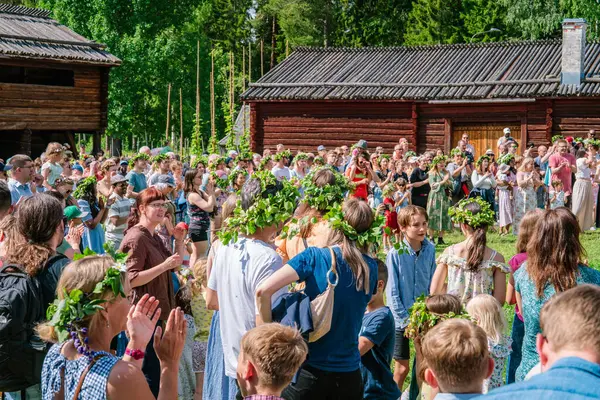 Turistler ve yerliler Gammlia, Umea, İsveç 'te yaz dönümünü dans ederken ve alkışlarken çiçek çelenkleri giyerek kutluyorlar. UMEA, GAMLIA, İSVEÇ 23 HAZİRAN 2023