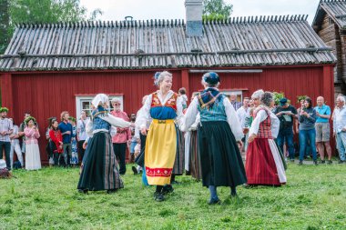 Geleneksel İsveçli kadınlar Gammlia 'da yaz ortası kutlamaları sırasında neşeli kostümler içinde dans ediyorlar. Umea. UMEA, GAMLIA, İSVEÇ 23 HAZİRAN 2023