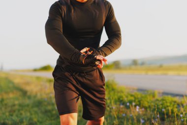 Genç bir atletin vücudu koşuyor ve elindeki akıllı saati kontrol ediyor. Yüksek kalite fotoğraf