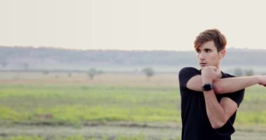 Portrait of muscular man in black t-shirt doing stretching exercises on street. His face is so serious. High quality 4k footage